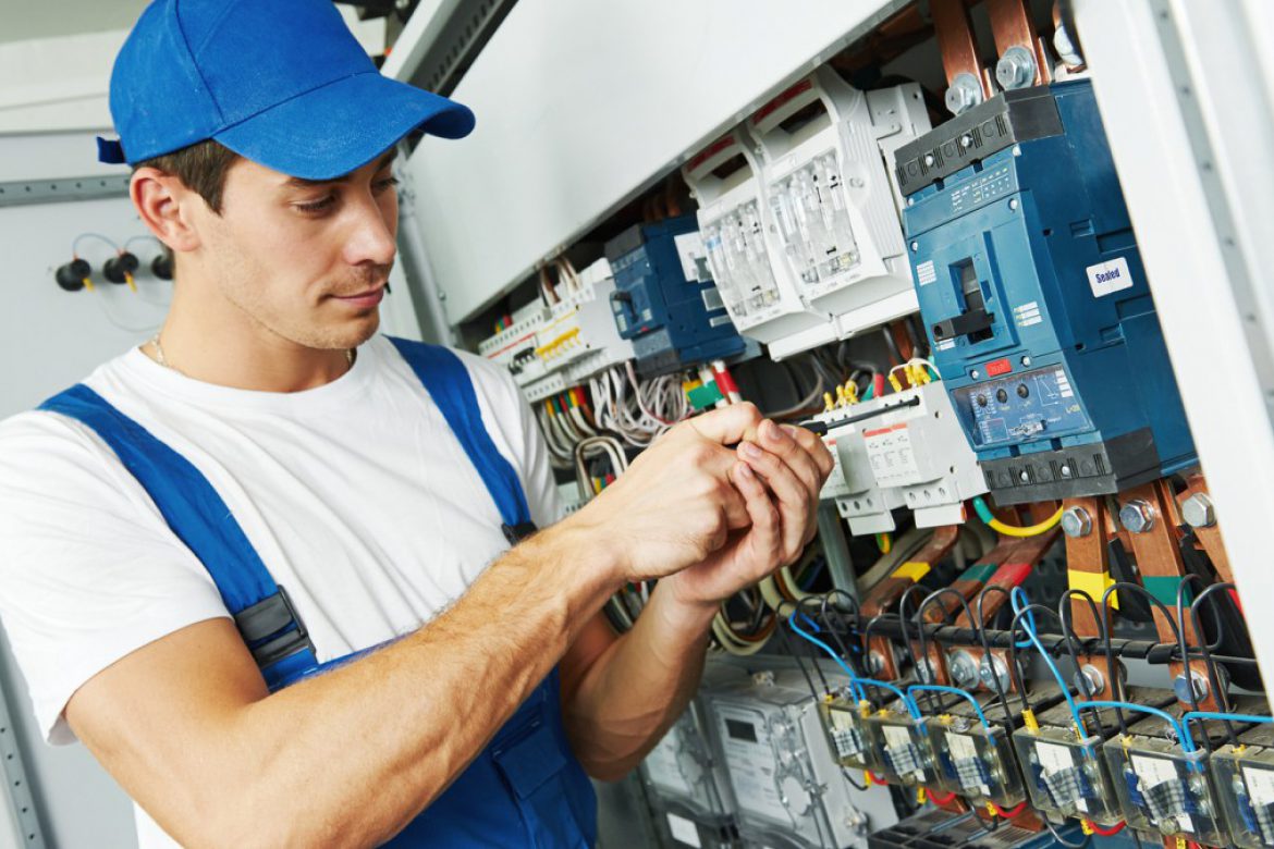 Young adult electrician builder engineer screwing equipment in f